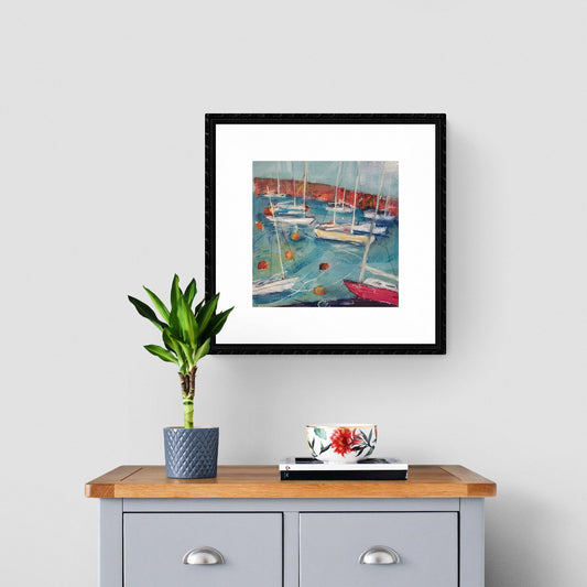 Painting of harbour on wall aove drawers with plant and teacup