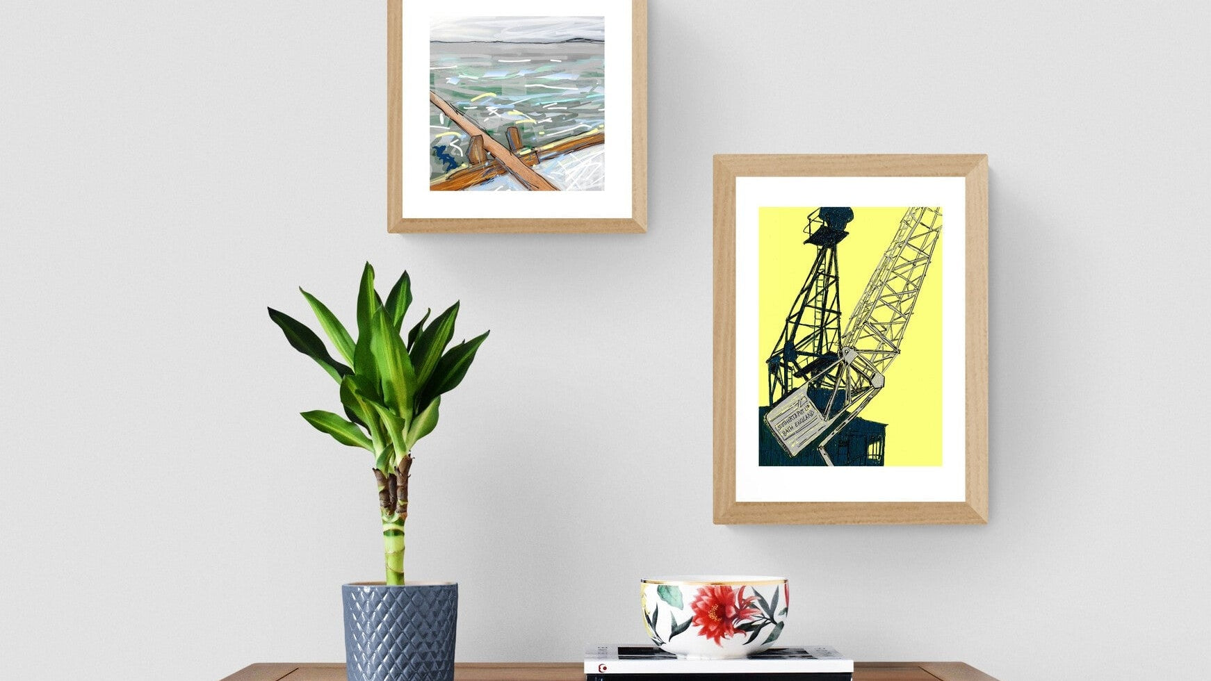 rowing boat and crane prints on grey wall with plant and chest of drawers