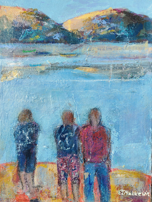 three people standing by a body of water with mountains in the background.